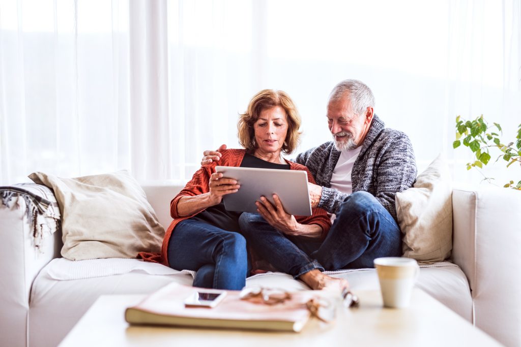 Senior couple with tablet relaxing at home.